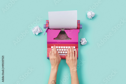 Woman writing on pink vintage typewriter photo