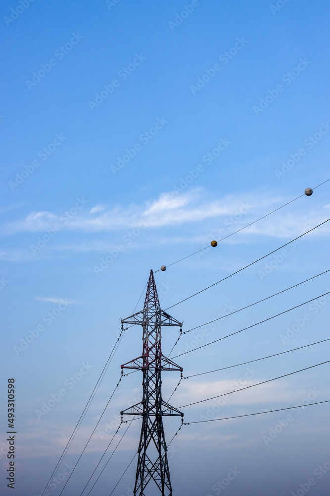 High voltage electricity transmission tower under the bright blue sky with copy space