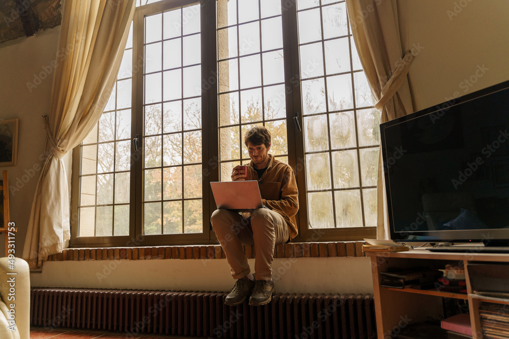 Portrait of man sitting by the window using laptop Portrait of man sitting by the window using laptop
