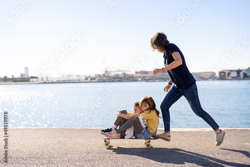 Mother and children riding skateboard on promenade photo