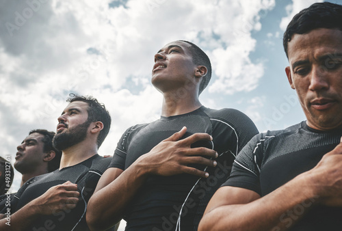 Standing proud. Cropped shot of a team of confident young rugby players standing at attention singing their anthem outside on a field before a rugby match. photo