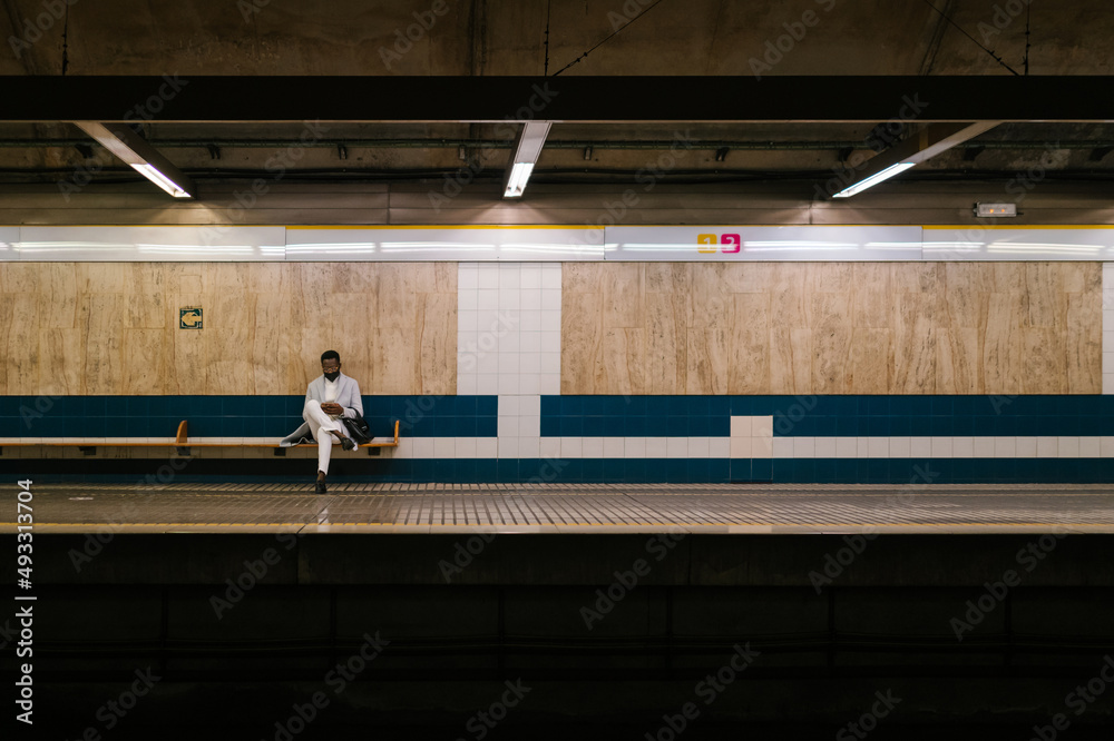 Man sitting alone on underground platform bench Stock Photo | Adobe Stock