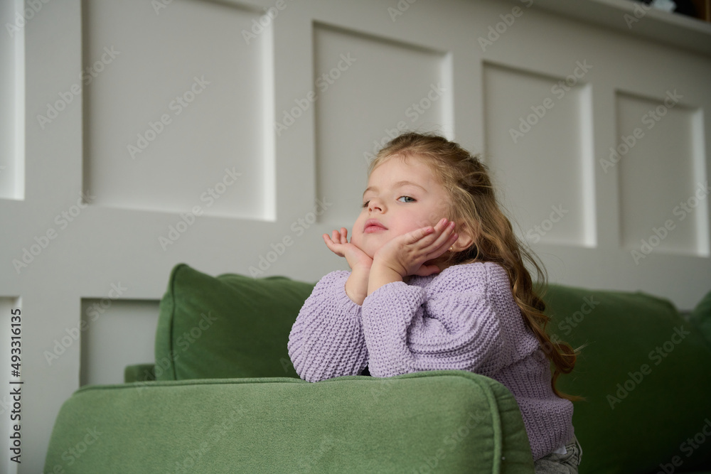 Cute young girl sitting in a chair looking bored. Cute young girl sitting in a chair looking bored.