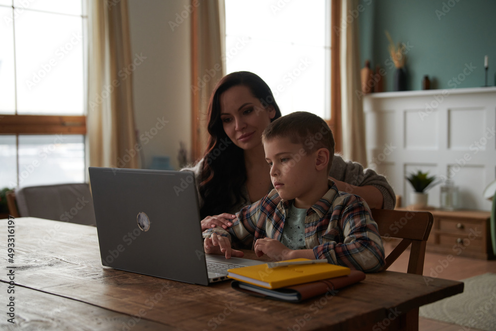 Mother helping her son to do homework.