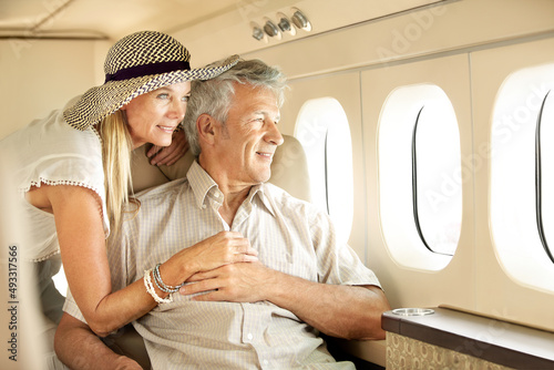 Taking a luxury trip. Smiling senior couple on an airplane looking out the window.