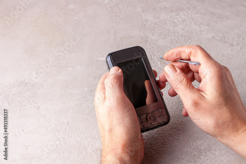 male hands holding smartphone with stylus photo