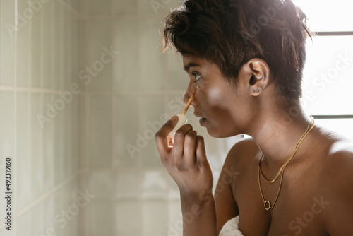 Young woman applying concealer in a bathroom