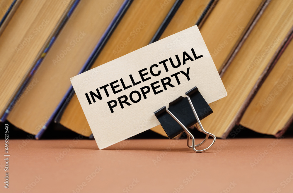 On the table against the background of books is a business card with the inscription - intellectual property