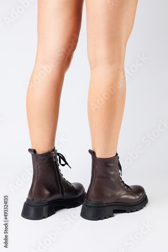 Women's brown spring boots made of genuine leather on a woman's leg. New collection of women's boots 2022