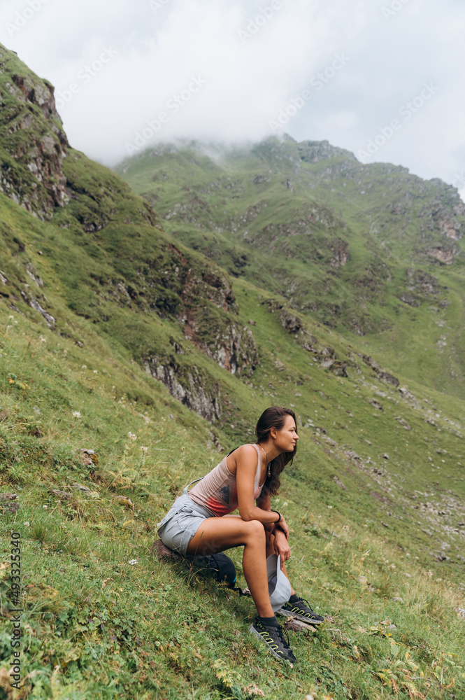 Young lady recreating on mountain slope during trekking Young lady recreating on mountain slope during trekking