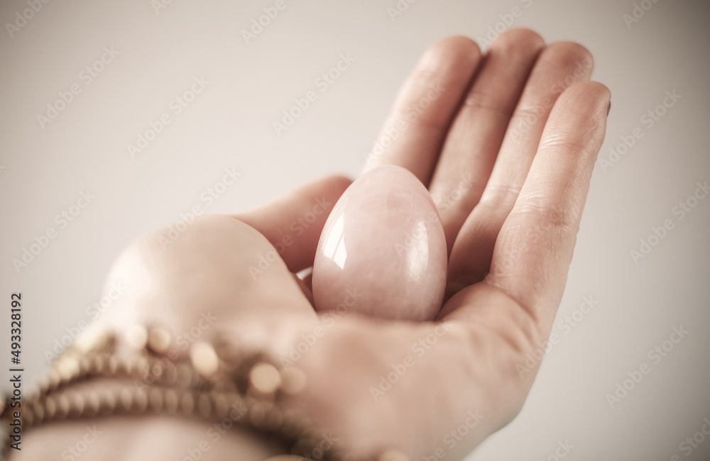 woman holding in hand a vaginal (yoni) egg. Rose quartz crystal jade egg. Copy space woman holding in hand a vaginal (yoni) egg. Rose quartz crystal jade egg. Copy space