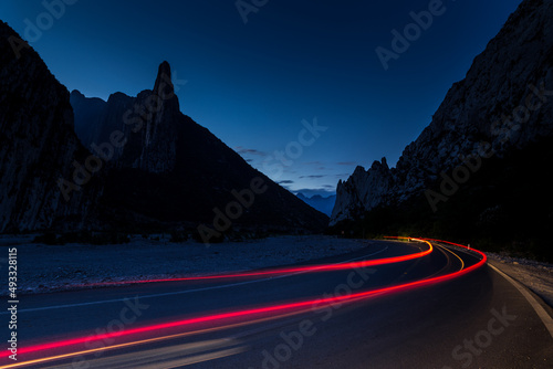 Fotografía de larga exposición con las luces traseras de un carro en una carretera vacía con montañas al fondo en Monterrey Nuevo León México (ID: 493328115)