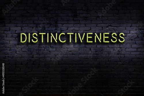 Neon sign. Word distinctiveness against brick wall. Night view