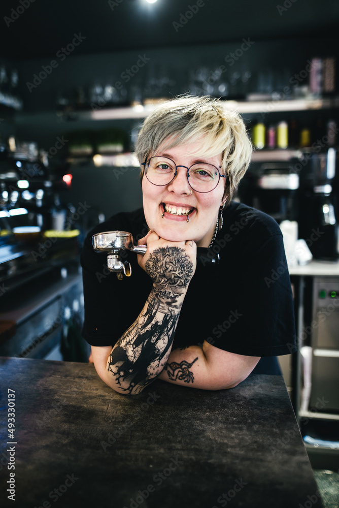 Smiling tattooed woman barista in cafe Smiling tattooed woman barista in cafe