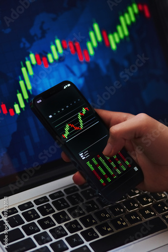 Businessman investor analyst using mobile phone analytics to analyze crypto currency financial market, trade data index chart graph on smartphone and laptop screen. close-up
