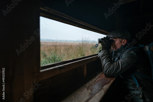 Man with binoculars in a wildlife hide. photo