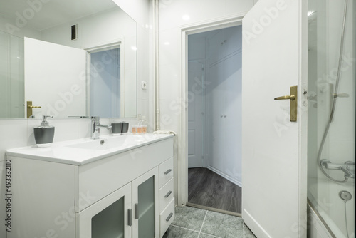 Bathroom with white resin vanity unit and sink, frameless rectangular mirror and walk-in shower with screen