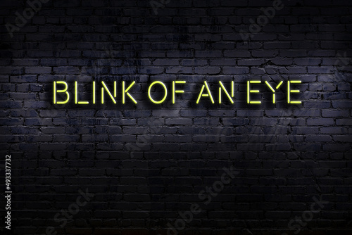 Neon sign. Word blink of an eye against brick wall. Night view photo