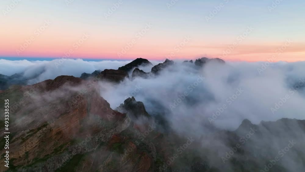 Top view of mountains of Madeira island. Fog moving fast over the mountains. Madeira island covered by clouds. Aerial view of Madeira mountains covered by cumulus clouds in the morning light.