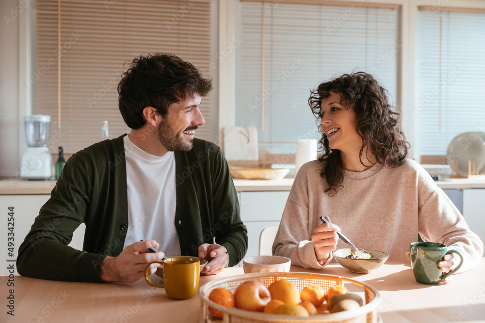 Smiling couple eating food for breakfast at home Smiling couple eating food for breakfast at home