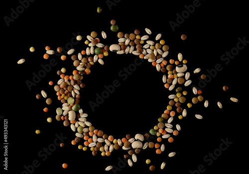 Mixed legumes and cereals, peeled barley, green, yellow and dark red lentils, half green peas, black white beans, green beans isolated on black, top view