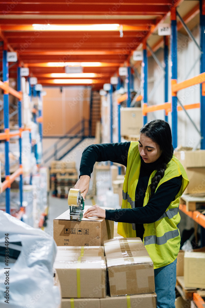 Woman sealing boxes with tape before shipping