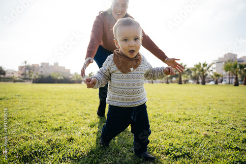 Cheerful mother chasing son in park photo