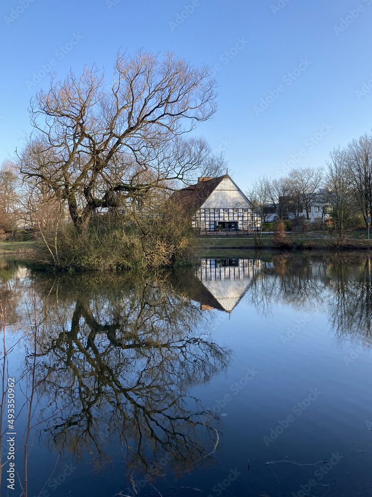 Saniertes historisches Bauernhaus in einem Park am Teich in Bielefeld im Winter, Nordrhein-Westfalen, Deutschland