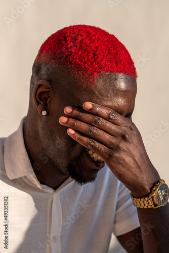 Joyful black man covering eyes while laughing merrily