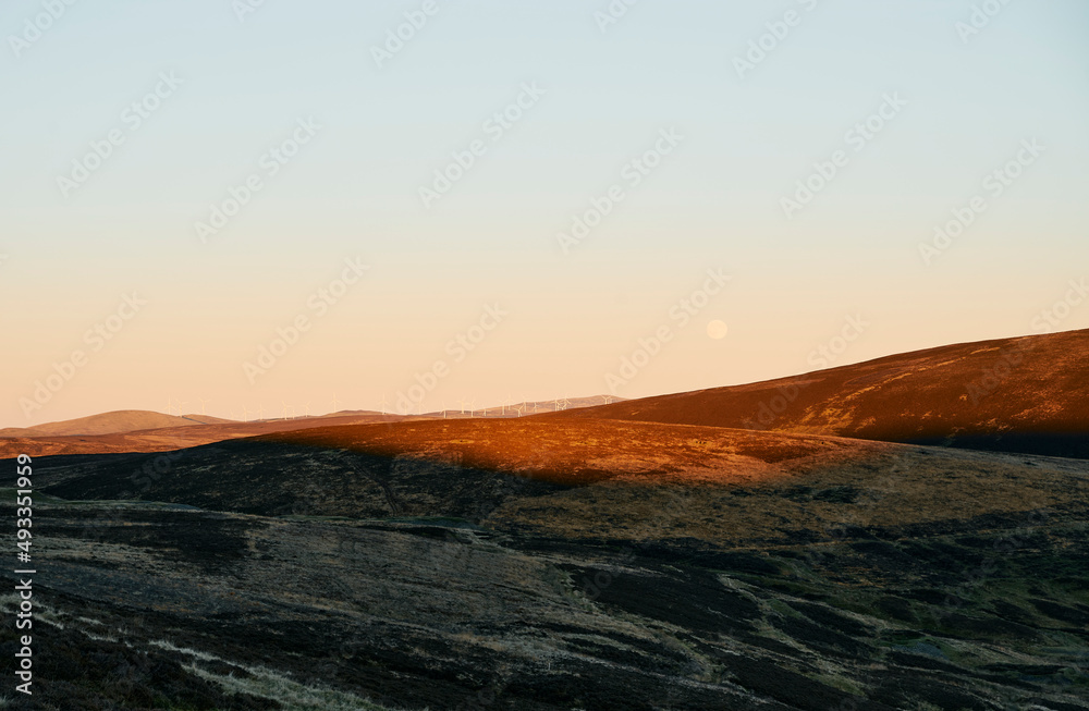 Moon over a remote Scottish windfarm at sunset