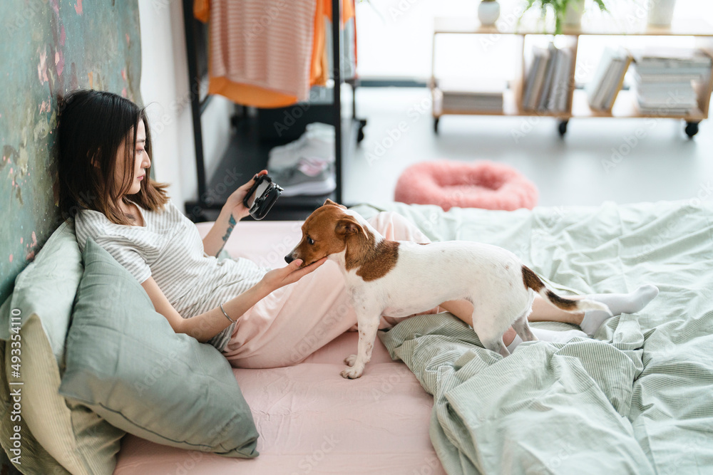 Woman with dog and smartphone chilling on bed Woman with dog and smartphone chilling on bed