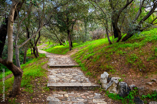 The shaded stone walking path and trail up Philopappos Hill towards the monument in the historic center of Athens, Greece. photo