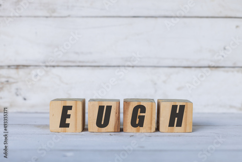 Eugh concept written on wooden cubes or blocks, on white wooden background. © Dionisio