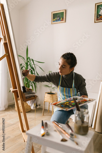 Young woman painting on canvas in art studio photo