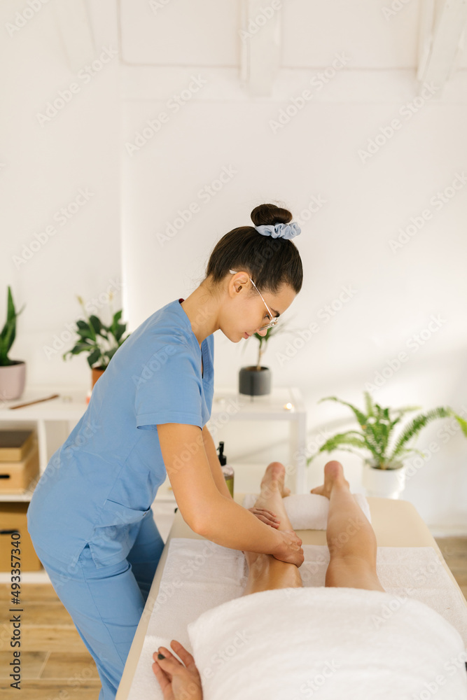 Massage therapist massaging a client in massage room Massage therapist massaging a client in massage room