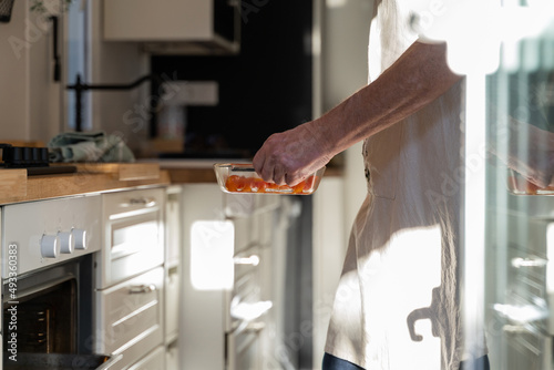 Senior man placing cooking tray inside ove photo