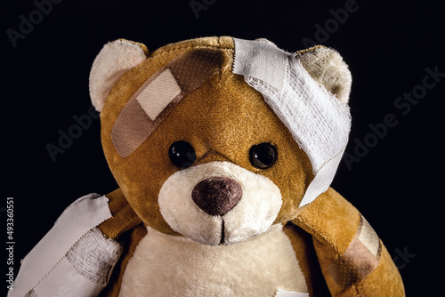 Fényképezés closeup of teddy bear bandaged with bandages and band aid, concept of child abus
