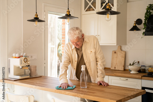 Active Senior man cleaning up kitchen counter top  photo