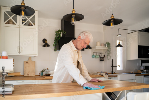 Senior man cleaning up kitchen counter top  photo