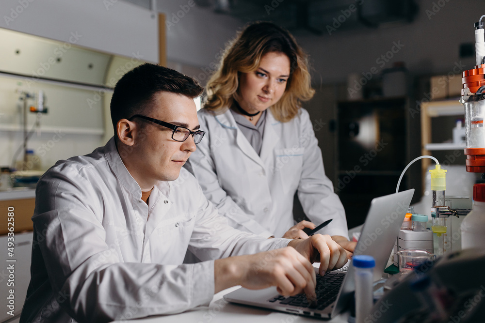 Lab workers doing research on laptop together Lab workers doing research on laptop together