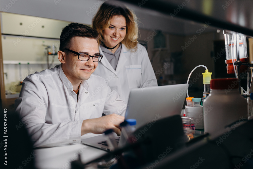 Positive colleagues working on laptop in laboratory Positive colleagues working on laptop in laboratory