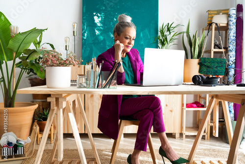 Stylish designer woman watching laptop in office photo