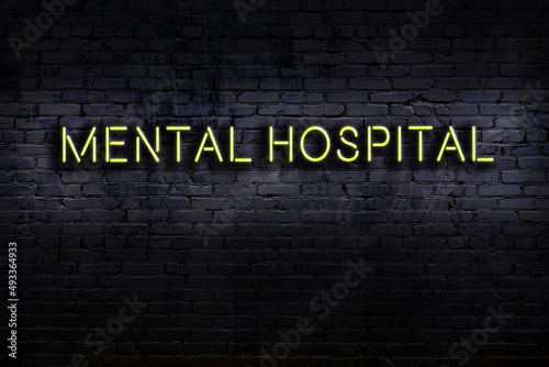 Schilderij op canvas Night view of neon sign on brick wall with inscription mental hospital
