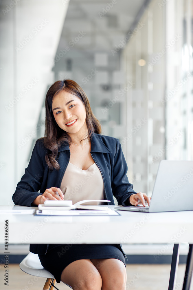 Charming Asian businesswoman sitting in the office with a digital laptop computer. Excited Asian businesswoman raising hands to congratulate while working in a modern office, Charming Asian businesswoman sitting in the office with a digital laptop computer. Excited Asian businesswoman raising hands to congratulate while working in a modern office,