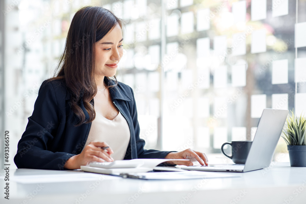 Charming Asian businesswoman sitting in the office with a digital laptop computer. Excited Asian businesswoman raising hands to congratulate while working in a modern office, Charming Asian businesswoman sitting in the office with a digital laptop computer. Excited Asian businesswoman raising hands to congratulate while working in a modern office,