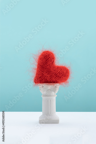 Red hand knit heart lying on antique column photo