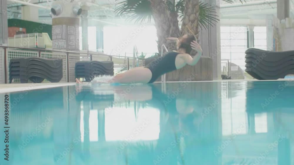 Young sexy attractive woman let herself fall off in to the swimming pool water, releasing fear and letting go anxiety and dive underwater set her free, slow motion