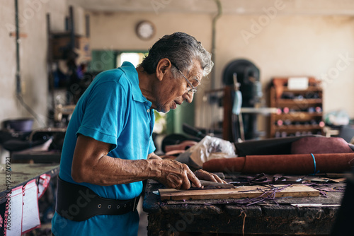 Hispanic senior shoemaker working in his workshop photo