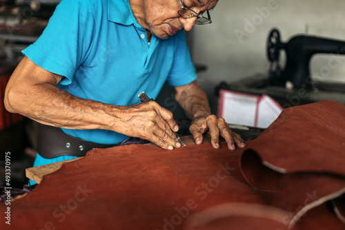 Hispanic senior shoemaker working the leather photo