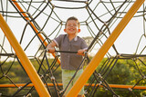Niño feliz contento jugando en el parque disfrutando escalando subiendo en los juegos infantiles con una gran sonrisa